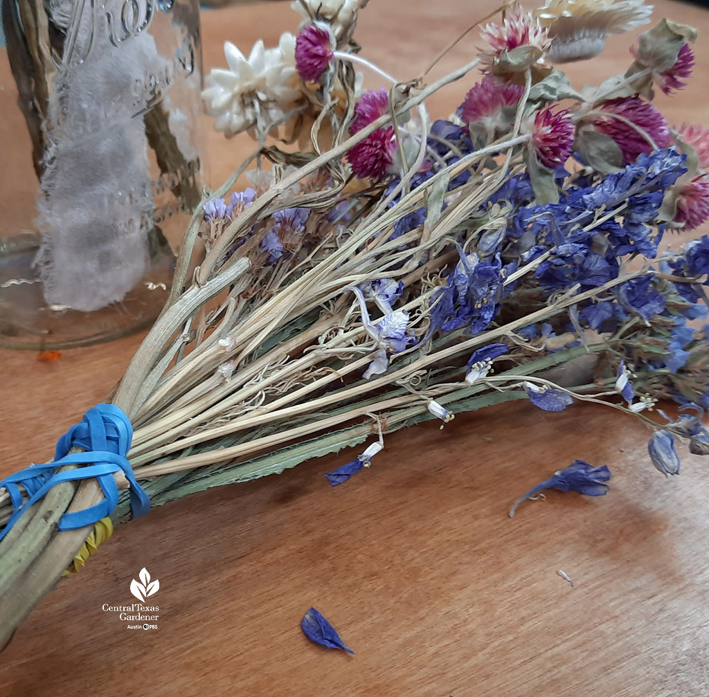 dried purple and deep blue flowers with long stems secured with blue rubber bands 