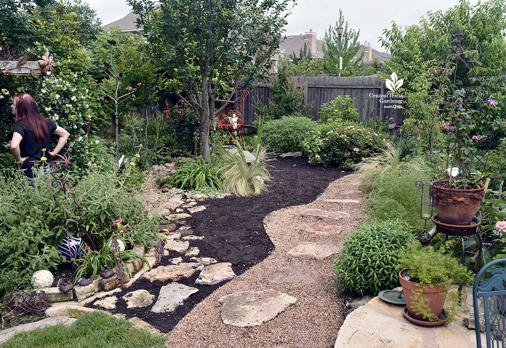 garden with gravel path running through swath of mulch, bordered by plants on  both sides 