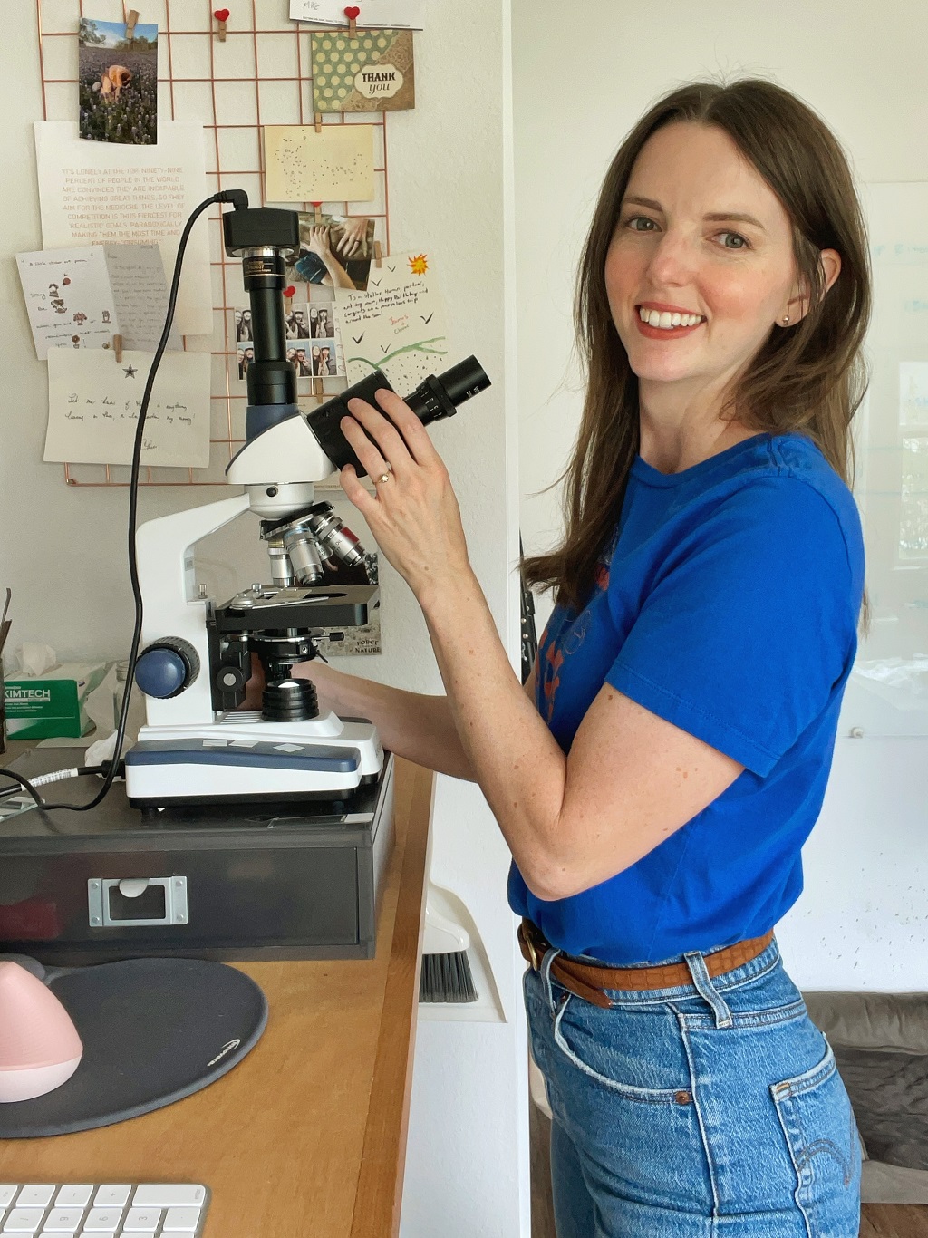 smiling young woman in blue t-shirt with a microscope