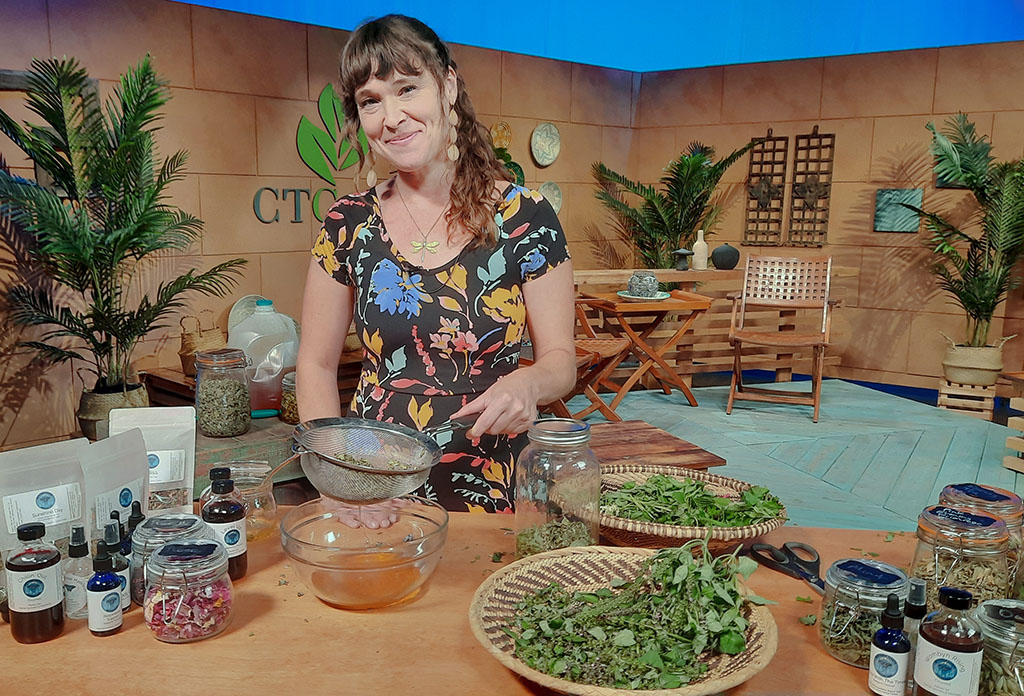 smiling woman on TV set with herbs on baskets and jars of honey
