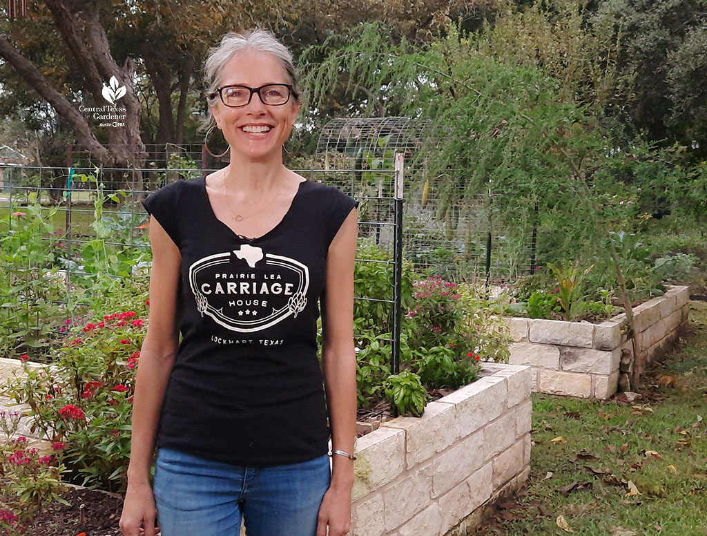 smiling woman in front of raised beds built of limestone blocks 