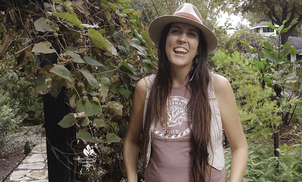 laughing young woman wearing hat in front of plants 