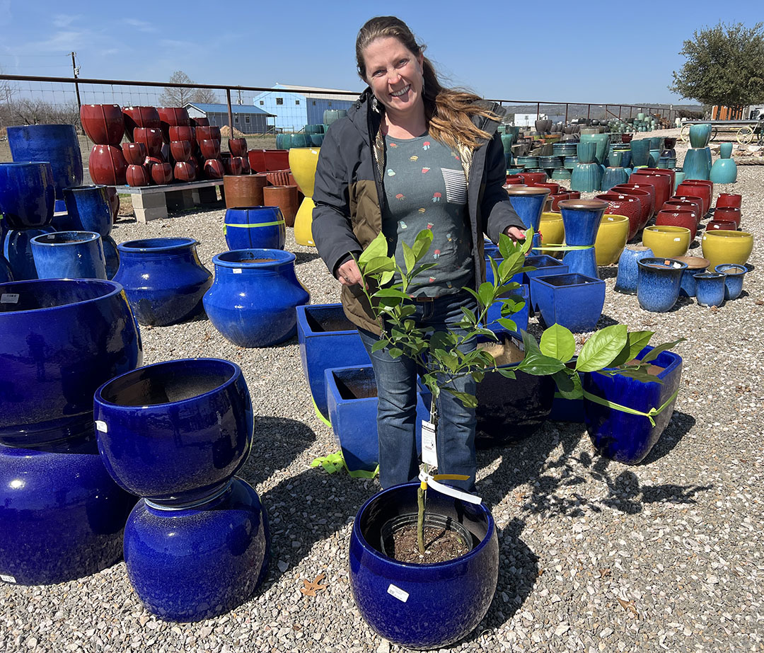 woman standing with many ceramic pots, demonstrating how to slip in black nursery pot plant