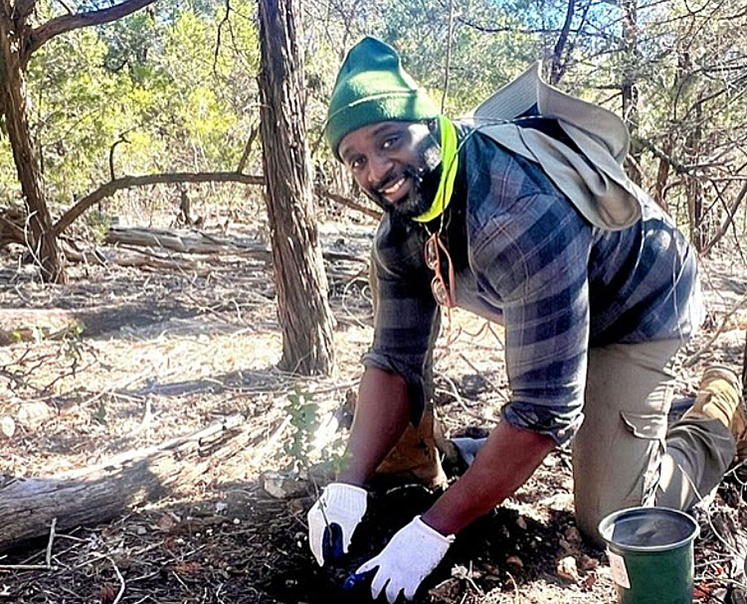 Black man working with mulch and soil in greenbelt 