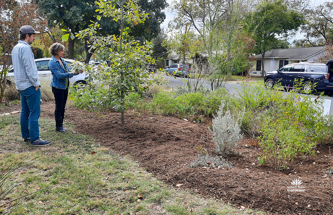 Paige with young man in front of rain garden planting 