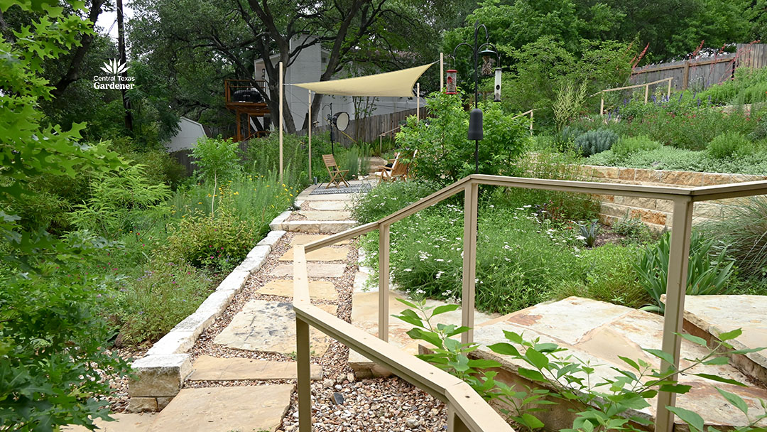 sandstone path bordered by flowers and small trees