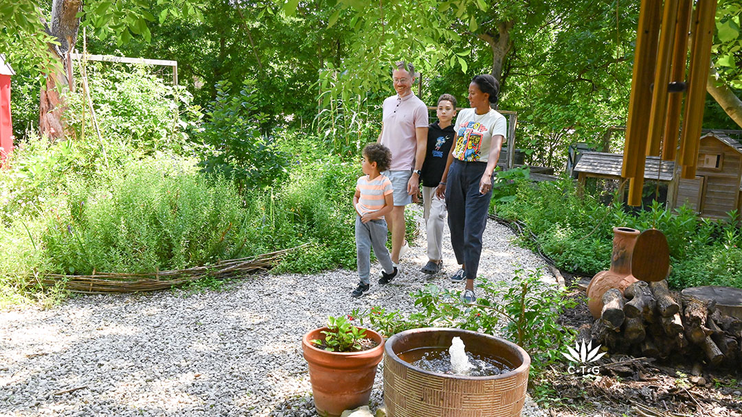 Richie and Nkiru walk gravel path and point out fun things to two young sons
