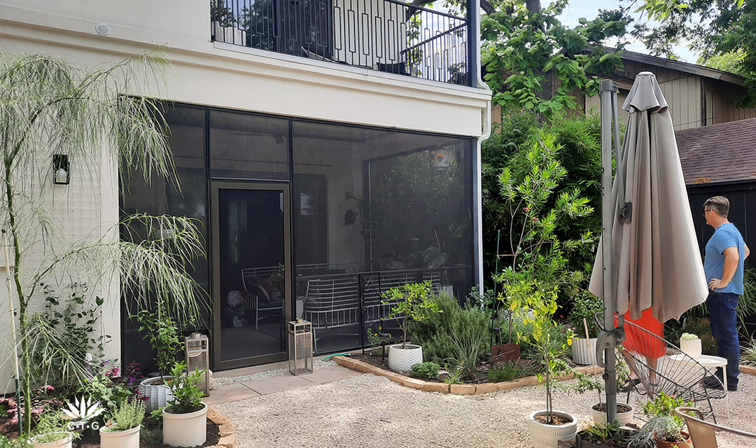 screened in porch with planting beds and small trees on each side