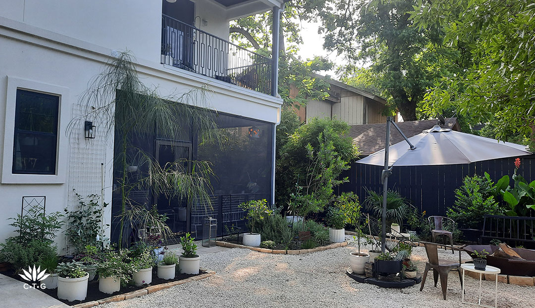 screened in porch framed by two planting beds and small trees 