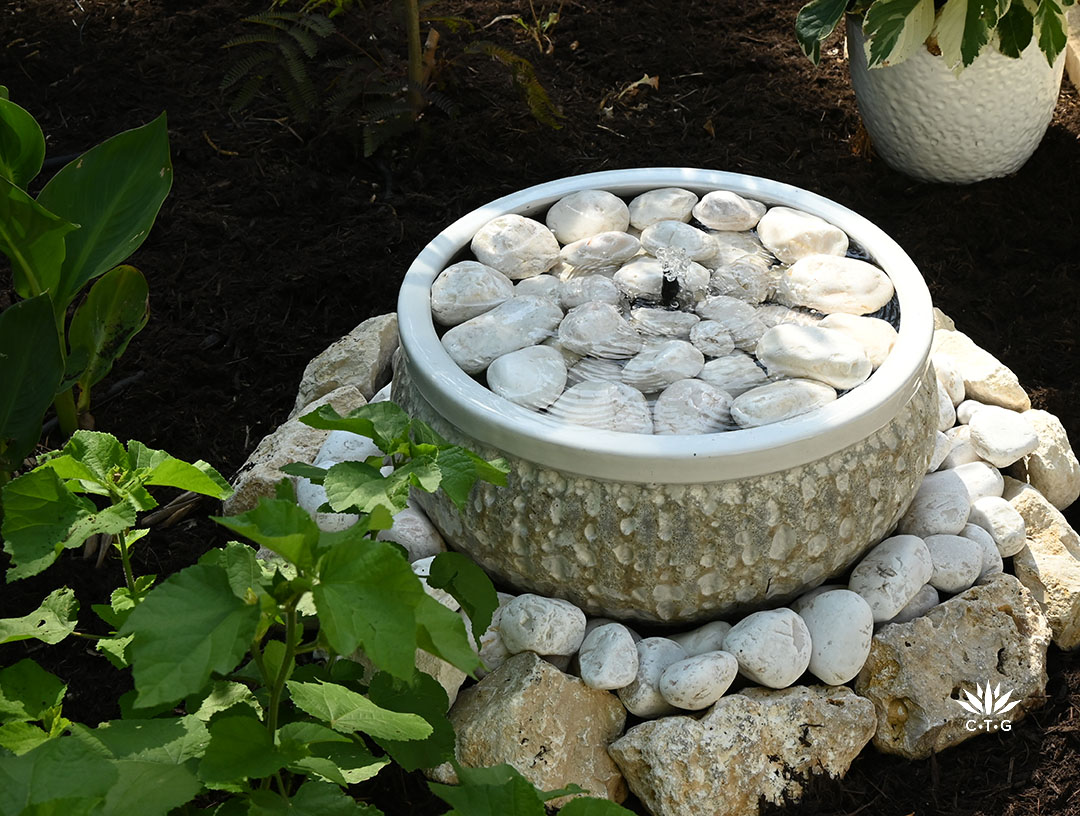 textured large round container filled with large white stones and small bubbling fountain 